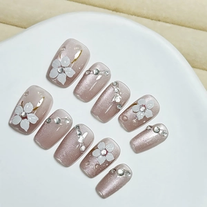Pink cat eye press-on nails with 3D white flower accents and sparkling rhinestones