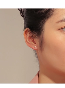 Close-up of curved 14K gold plated silver stud earrings with inlaid zircon on ear
