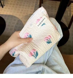 Close-up of quilted cream makeup bag with pink cherry pattern held in hand