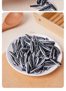 Realistic PVC sunflower seeds on a white plate with a wooden spoon for photography props
