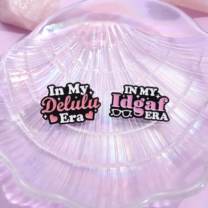 Colorful ERA series enamel pins featuring In My Delulu and Idgaf slogans on shell tray