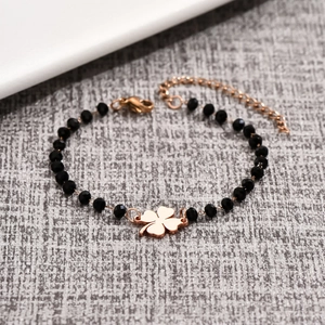 Detail of beaded bracelet with black faceted stones and a rose gold clover charm