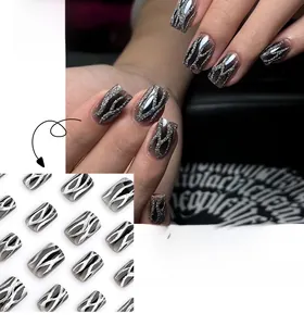 Detail of short square press-on nails featuring black smudge design and silver glitter flames