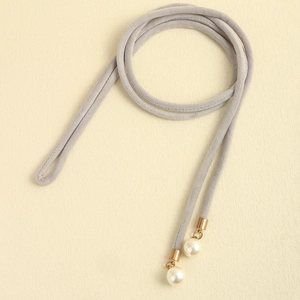 Detail of grey velvet waist rope featuring elegant pearl pendants and gold metal caps