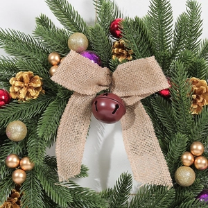Christmas wreath with green pine needles, golden pine cones and a rustic burlap bow