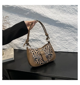 Detail of leopard print shoulder bag with brown leather trim and golden metal buckle
