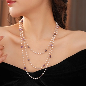 Detail view of multi-layered pearl necklace with purple amethyst and gold metal chain