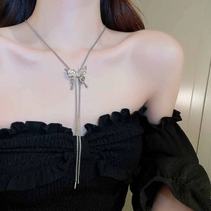 Detail of silver butterfly tassel necklace worn by a model against a black dress