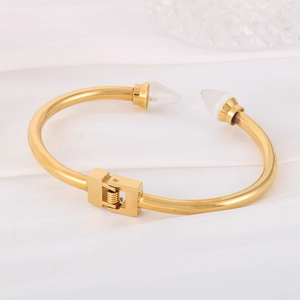 Detail of gold stainless steel bangle featuring white cone studs and mechanical spring lock