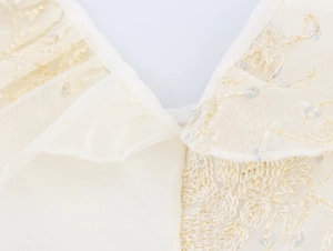 Gros plan sur la broderie dorée et les paillettes transparentes sur tulle champagne