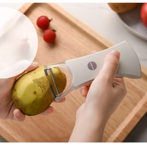 Close-up of a white ergonomic vegetable peeler removing potato skin in a kitchen setting