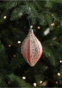 Pink starburst Christmas ornament with silver glitter stripes hanging on a tree