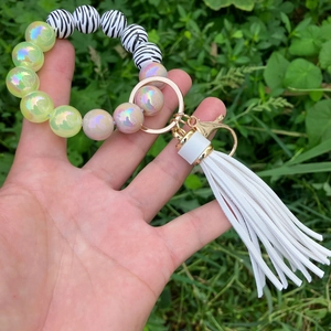 Luminous beaded bracelet keychain with zebra prints, white tassel, and gold hardware