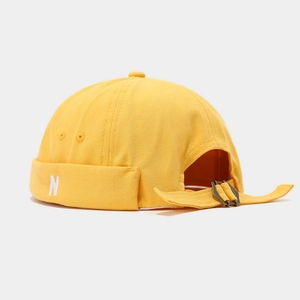 Macro detail of yellow docker hat featuring N embroidery and adjustable metal buckle