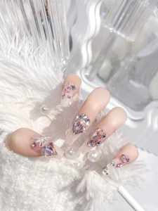 Macro shot of long coffin nails with pink rhinestones, pearls and silver bow charm detail