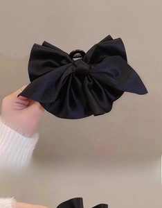 Grande molletta per capelli con fiocco di raso nero mostra texture elegante e impugnatura
