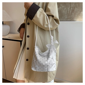 Polka dot bucket bag with lace bow decoration shown in a lifestyle shoulder carry view