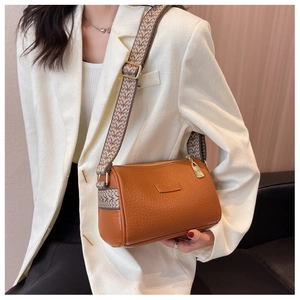 Braune Boston Bag aus Leder mit Vintage Gurt getragen über einem weißen Blazer