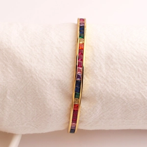 Macro detail van gouden C-vormige armband met regenboog pave gezette gekleurde zirkonia
