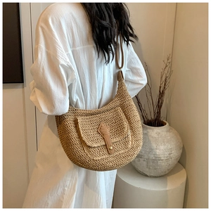Detailed close-up of woven straw texture and brown leather strap on hobo bag