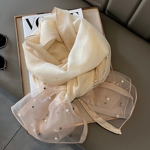 Detail of champagne silk scarf with pearl embellishments and metallic studs on mesh