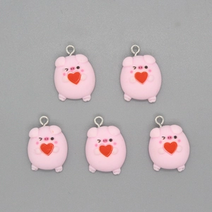 Close-up of five pink resin pig pendants with red hearts and metal loops for DIY jewelry