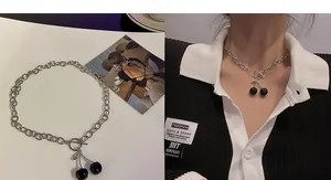 Detail of silver OT buckle necklace with shiny black cherry pendants for a hip-hop style look