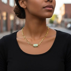 Detail of gold paperclip chain necklace with green evil eye pendant on a model's neck
