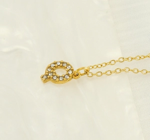 Macro detail of gold letter P pendant necklace with sparkling diamonds on satin