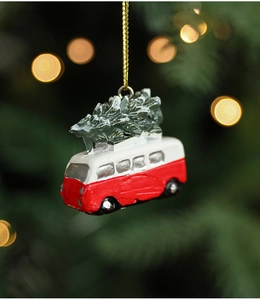 Close-up of a resin red vintage bus ornament with snowy trees for Christmas decor