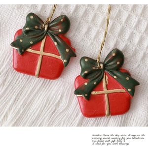 Close-up of red Christmas gift box charms with green polka dot bows on white knit