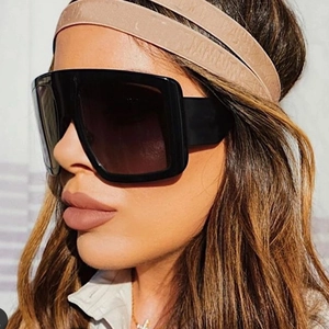 Close-up of oversized black square frame sunglasses with seamless shield lens on model