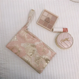 Macro shot of pink and gold floral jacquard phone bag with texture and wristlet detail