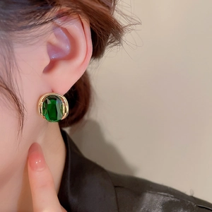 Elegant gold earrings with oval green emerald zircon shown on model for women