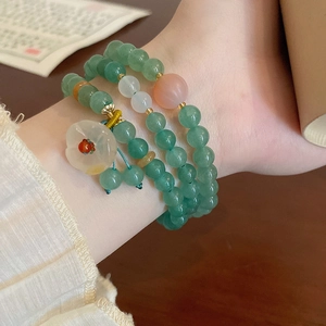 Nahaufnahme der mehrlagigen smaragdgrünen Perlenarmkette mit Blumenanhänger und Quaste