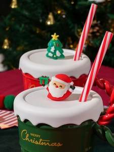 Detail of red and green Christmas ceramic mugs with Santa lids and striped straws