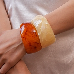Modern wide resin bangles with marble texture in amber and cream displayed on a model
