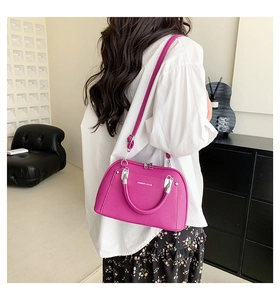 Détail du sac à main rose rouge texture litchi avec boucles en argent porté par un mannequin