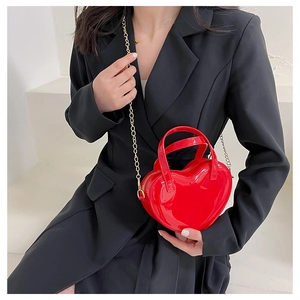 Red heart-shaped jelly bag in patent leather with gold chain strap on model