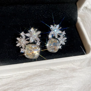 Vue macro de boucles d'oreilles fleur en zircon carré champagne sur velours noir