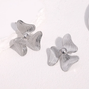 Minimalist silver flower stud earrings with wavy petals and center bead on white surface