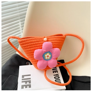 Detail der orangefarbenen Stroh-Umhängetasche mit rosa 3D-Blume und Perlenknopf-Verschluss