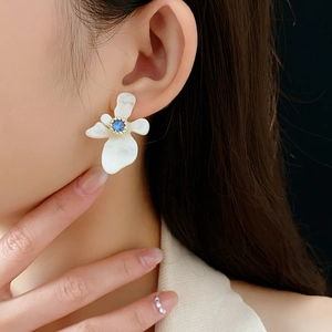 Gros plan d'une boucle d'oreille fleur en résine avec pierre bleue sur un mannequin