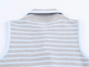 Dettaglio del gilet in maglia a righe azzurre e grigie con scollo rotondo a costine