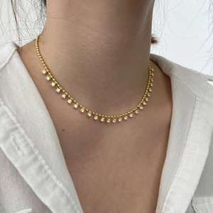 Detail of elegant gold-tone necklace with olive leaf tassels and sparkling zircon stones
