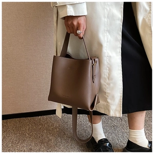 Detail view of coffee brown leather bucket bag showing matte texture and side carry strap