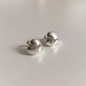Macro shot of minimalist silver heart-shaped stud earrings in polished 925 sterling silver