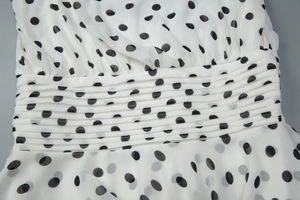 Detailed macro view of the ruched waistline on a white and black polka dot A-line dress