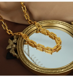 Detail of gold rectangular link chain necklace on vintage mirror with satin fabric