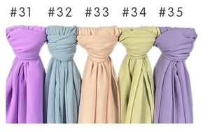 Detail showing five different solid color pearl chiffon scarves tied neatly on white background